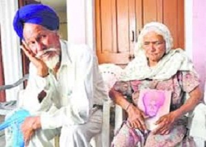 Kuldip Singh's mother holds his picture as father Ajaib Singh looks on at Amrali village in Ropar. [FILE PHOTO]