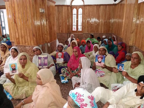 Family members of victims of human rights abuses in Punjab holding pictures of their relatives who were subjected to enforced disappearance in Punjab