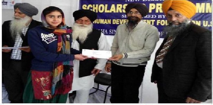 A student is receiving scholarship check from Sikh Human Development Foundation