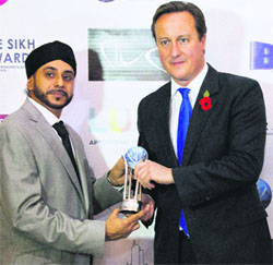 British PM David Cameron receives the Sikh Award from Navdeep Singh, the award founder, in London on November 08, 2013