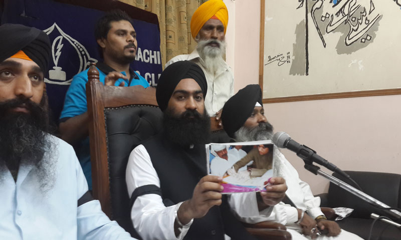 Chairman Pakistan Sikh Council Ramesh Singh showing pictures of the alleged desecration at a press conference in Karachi on August 27, 2013